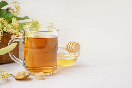 Glass cup of linden tea and bowl with honey on white backgroundの写真素材