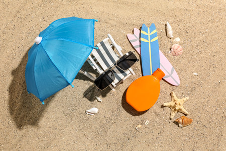 Creative composition with sunglasses, bottle of sunscreen cream, mini deckchair and surfboards on...