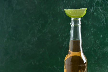 Bottle of cold beer with lime on green backgroundの写真素材