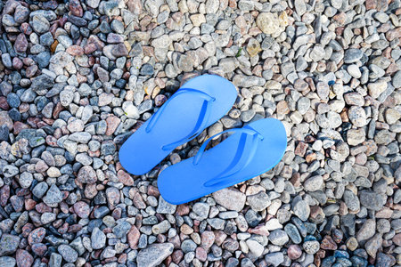 Blue flip-flops on rocky beachの写真素材
