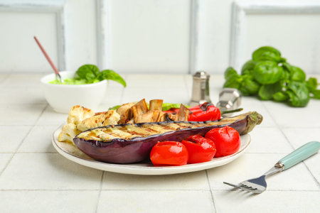 Plate with grilled vegetables and basil on white tile tableの写真素材