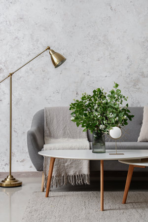 Interior of living room with cozy gray sofa and blooming jasmine flowers on coffee tableの写真素材