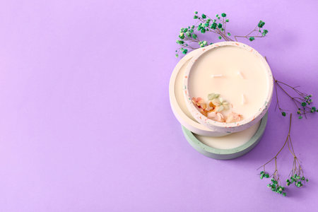 Holders with candles and flowers on lilac backgroundの写真素材
