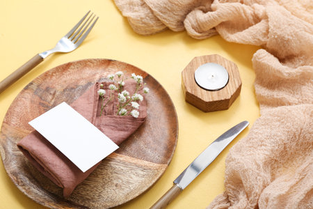 Beautiful table setting with gypsophila flowers, blank invitation card and candle on yellow tableの写真素材