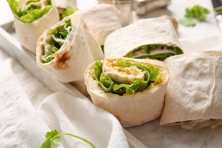 Plate of tasty lavash rolls with egg, onion and greens on tableの写真素材