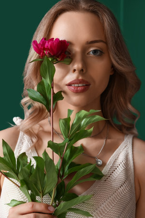 Young woman with beautiful peony flower near green wall, closeupの写真素材