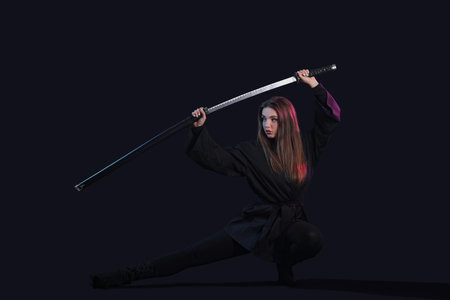 Beautiful sexy young woman with katana on dark backgroundの写真素材