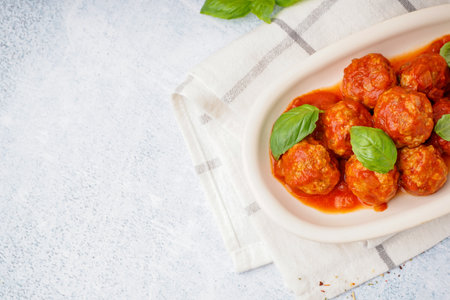 Plate of tasty meat balls with tomato sauce and basil on gray tableの写真素材