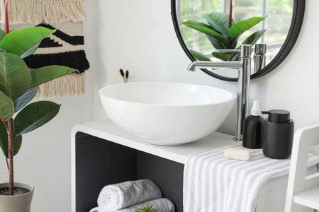 Sink bowl, soap bar, towel and bath accessories on shelving unit in bathroomの写真素材