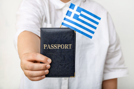 Woman holding passport with flag of Greece on white backgroundの写真素材