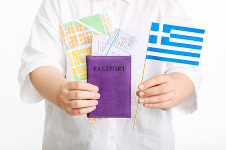 Woman holding passport, flag of Greece, map and tickets on white background. tourism conceptの写真素材