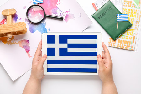 Woman holding tablet computer with flag of Greece near world map and passport on white background. travel conceptの写真素材