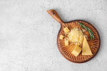Wooden board with tasty Swiss cheese on light backgroundの写真素材