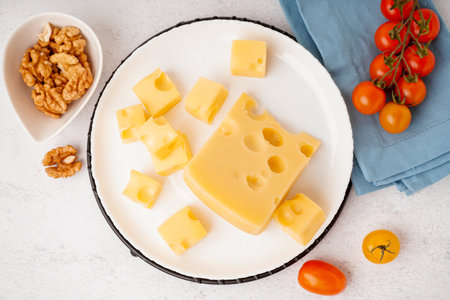 Stand and plate with pieces of Swiss cheese and tomatoes on white tableの写真素材