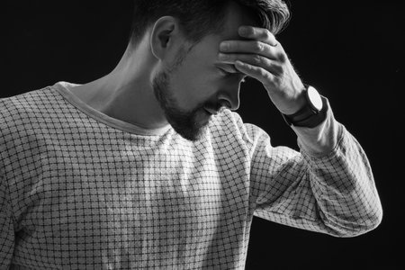 Young man having panic attack on black background, closeupの写真素材