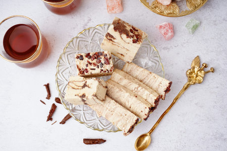 Pieces of tasty marble halva and glass with Turkish tea on light background