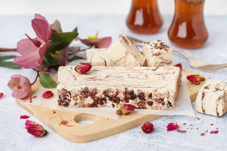 Wooden board with pieces of tasty marble halva on light backgroundの写真素材