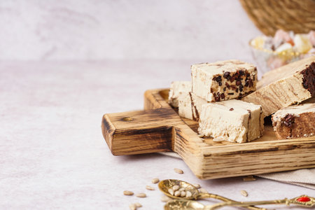 Wooden board with pieces of tasty marble halva on light backgroundの写真素材