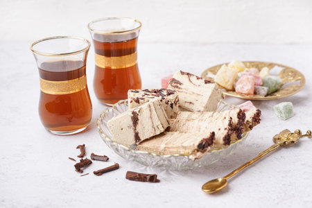 Pieces of tasty marble halva and glasses with Turkish tea on light backgroundの写真素材