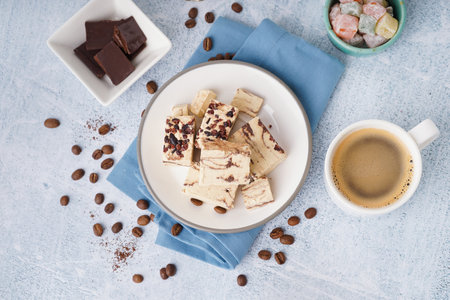 Pieces of tasty marble halva and cup with coffee on light backgroundの写真素材