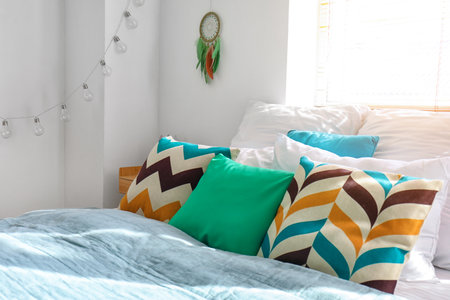 Interior of modern bedroom with bed and dream catcher hanging on white wallの写真素材