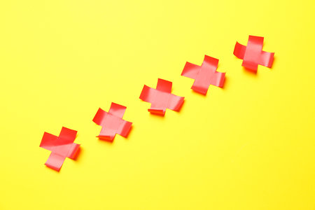Red crosses made of adhesive tape on yellow backgroundの写真素材