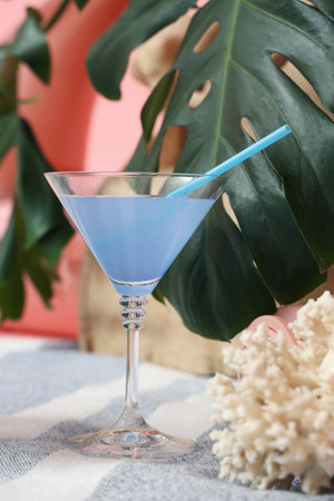 Cocktail with palm leaves and coral on beach blanket against pink background. travel conceptの写真素材