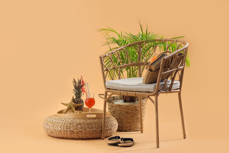 Chair with beach accessories, cocktail, pineapple and plant on pale orange background. travel conceptの写真素材