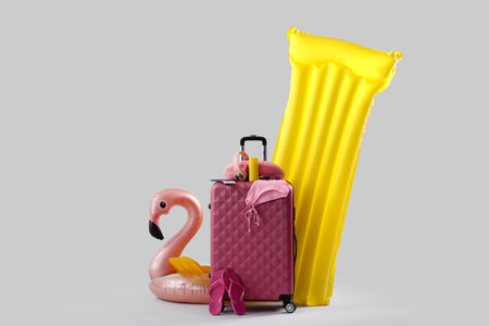 Suitcase with beach accessories, passport, inflatable ring and mattress on gray background. travel conceptの写真素材