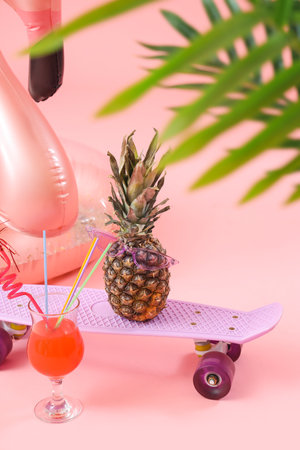 Inflatable ring with cocktail, skateboard and pineapple on pink background. travel conceptの写真素材