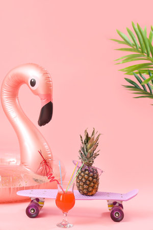Inflatable ring with cocktail, skateboard and pineapple on pink background. travel conceptの写真素材