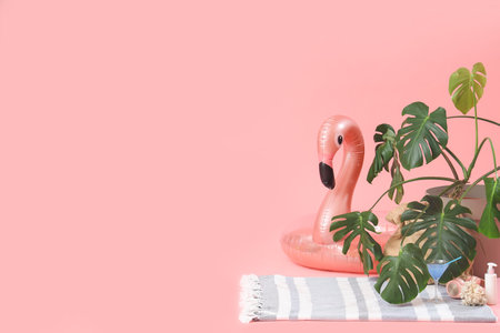 Inflatable ring in shape of flamingo with plant, cocktail and sunscreen cream on pink background. travel conceptの写真素材