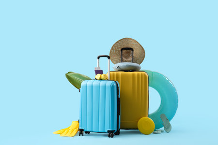 Suitcases with inflatable ring, passport and beach accessories on blue background. summer vacation conceptの写真素材