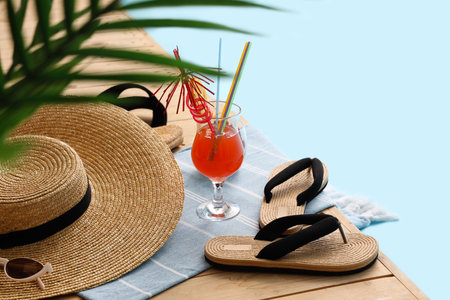 Different beach accessories with plant branches and cocktail on wooden pontoon against blue background. summer vacation conceptの写真素材