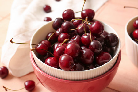 Bowl with sweet cherry on pink tile tableの写真素材