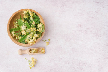 Wooden bowl with fresh linden flowers on light backgroundの写真素材