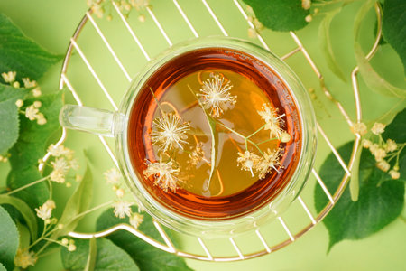 Stand with glass cup of linden tea on green backgroundの写真素材