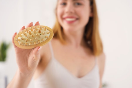 Young woman with anti-cellulite brush in bathroom, closeupの写真素材