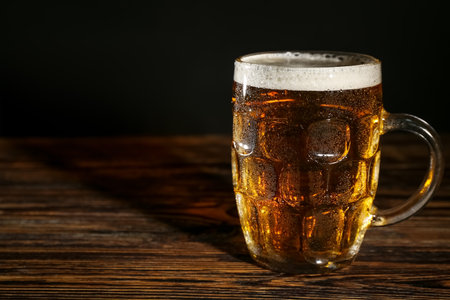Mug of cold beer on wooden tableの写真素材