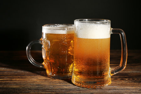 Mugs of cold beer on wooden table, closeupの写真素材