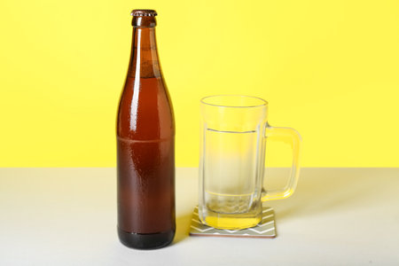Bottle of cold beer and mug on color backgroundの写真素材