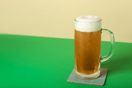 Mug of cold beer on color backgroundの写真素材