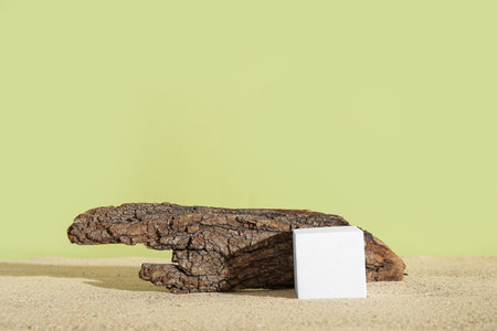 Decorative plaster podium with tree bark on sand against olive backgroundの写真素材