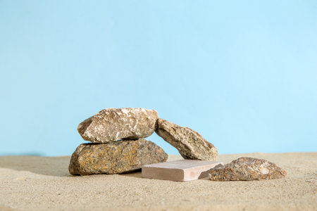 Decorative plaster podium with stones on sand against blue backgroundの写真素材