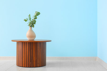 Wooden coffee table with eucalyptus branches in vase near blue wallの写真素材