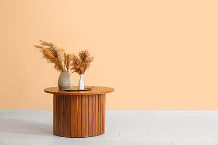 Vases with pampas grass on wooden coffee table near beige wallの写真素材