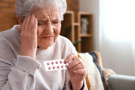 Ill senior woman with pills at home, closeupの写真素材