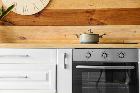 Modern electric oven with cooking pot near wooden wallの写真素材