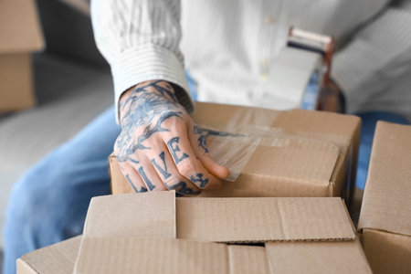 Young man tapping box in room on moving day, closeupの写真素材