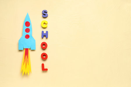 Paper rocket with word SCHOOL on beige background